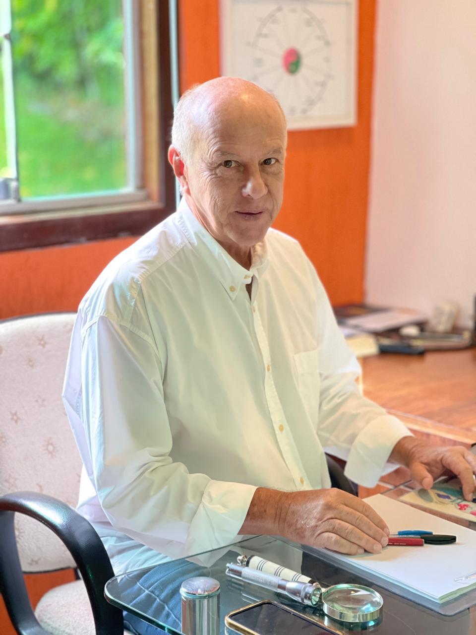 Pete Coe em seu consultório, sentado à mesa de atendimento
